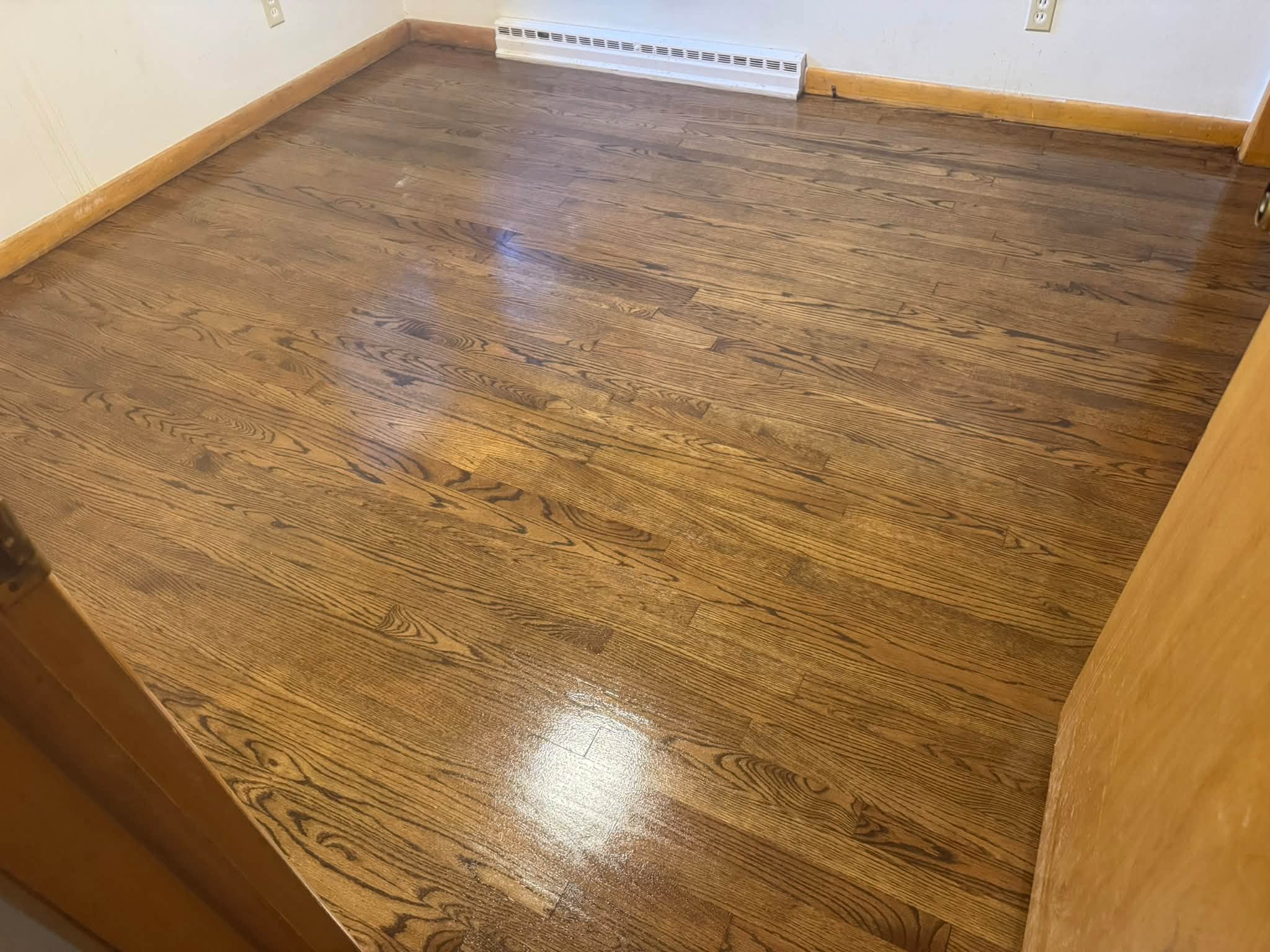 The same hardwood floor after refinishing, with a darker glossy finish