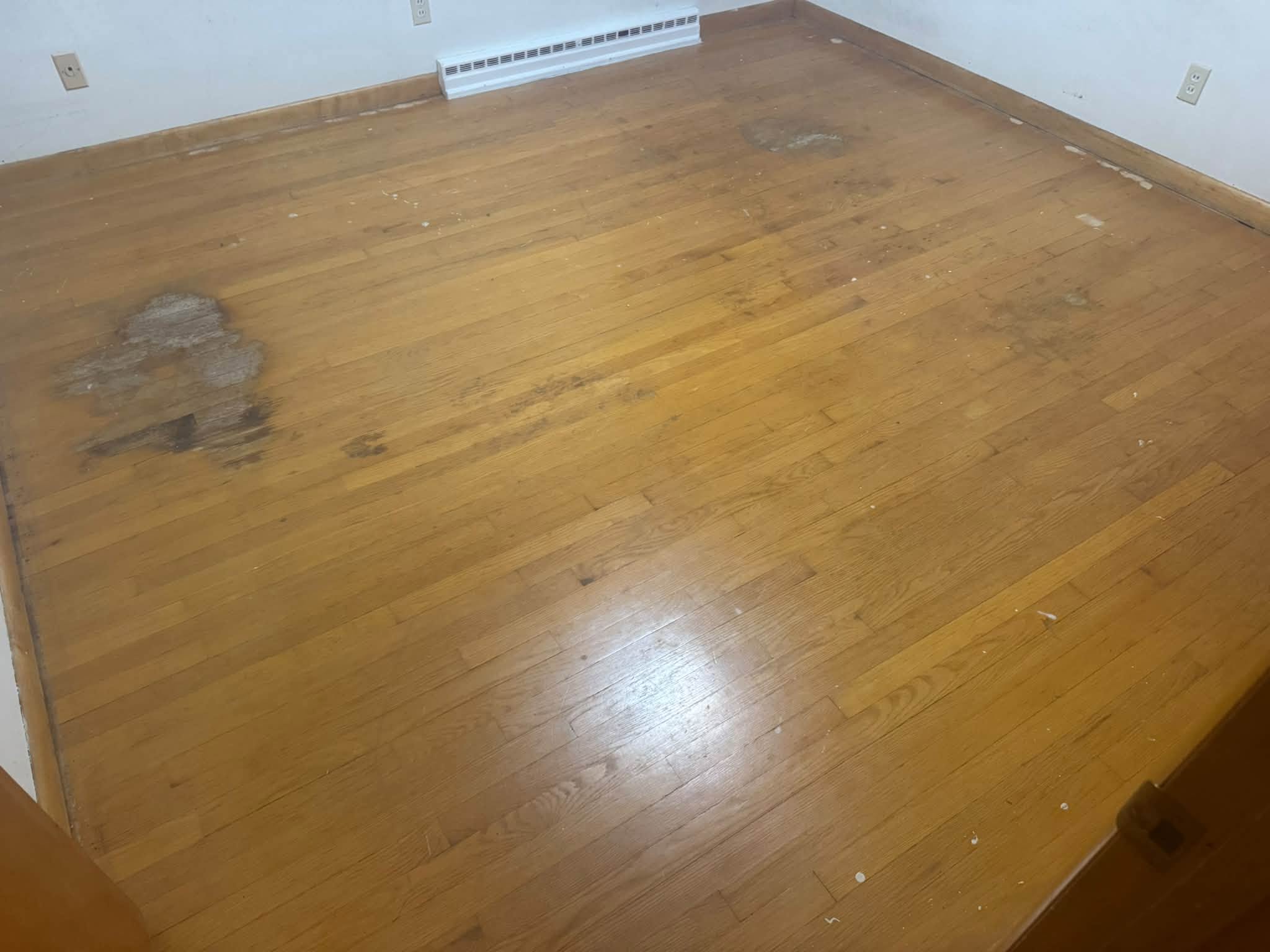 Worn hardwood floor before refinishing, with dull and stained areas